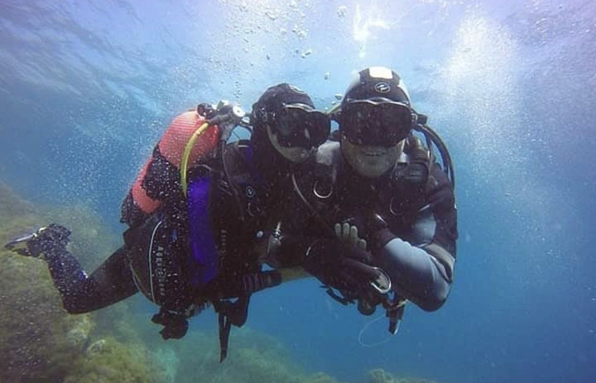 Two scuba divers underwater, side by side, looking at the camera